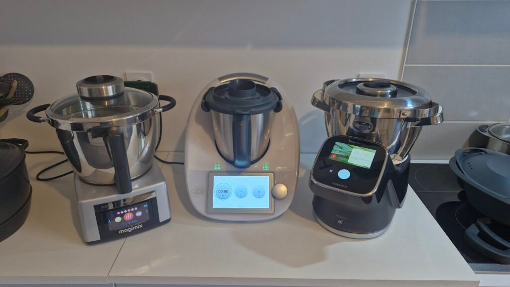 Photographie de 3 robots cuiseurs haut de gamme : le Thermomix TM6, Le Cook Expert de Magimix et le I Companion Touch Pro de Moulinex