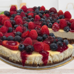 Cheesecake pour 12 personnes avec une base spéculoos, aux fruits rouges : fraises, myrtilles et framboises avec un coulis de framboises.