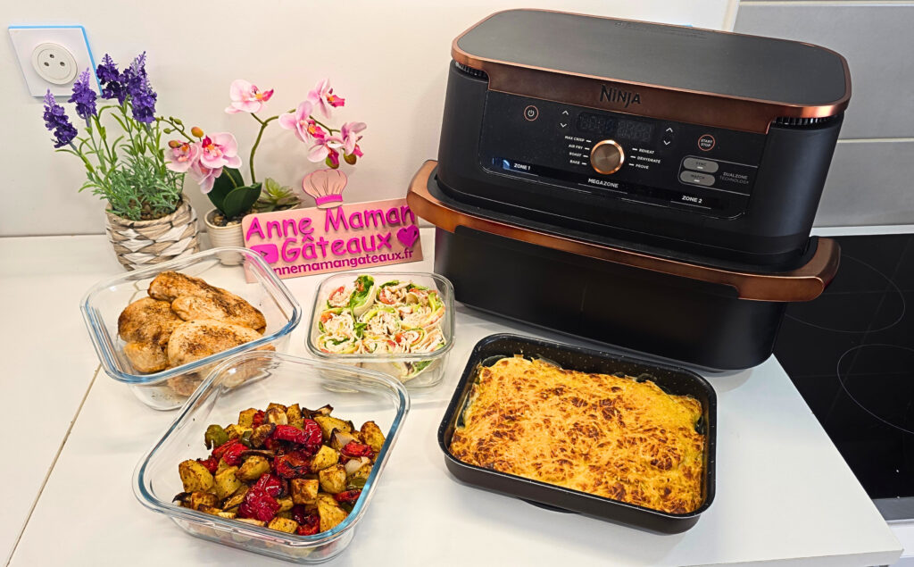 batch cooking à l'airfryer : un gratin de courgettes dans un moule rectangulaire, des filets de poulet grillés dans un plat de conservation carré en verre, des légumes rôtis à savoir poivrons, oignons et pommes de terre dans un plat carré en verre et des wraps garnis de poulet, concombre, tomates et sauce au yaourt coupés en deux rangés dans un plat en verre carré également.