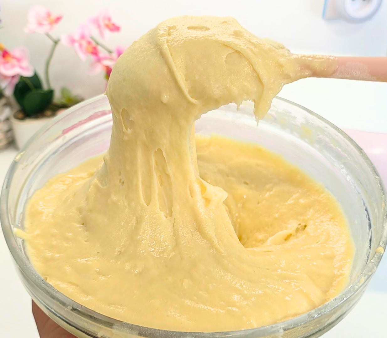 saladier plein d'une pâte à gâteau soulevée par une spatule rose